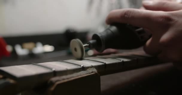 Luthier memoles frets baru pada fretboard gitar di alat musik repairshop, 4k 60fps Prores HQ — Stok Video