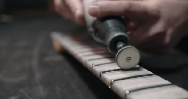 Luthier pule nuevos trastes en el diapasón de la guitarra en el taller de reparación de instrumentos musicales, 4k 60fps Prores HQ — Vídeo de stock