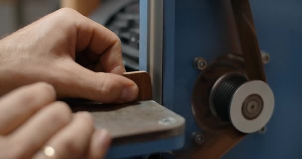 Carpenter utiliza lijadora de cinta en su taller para procesar los pequeños elementos de madera, 4k 60p 10 bit — Vídeo de stock