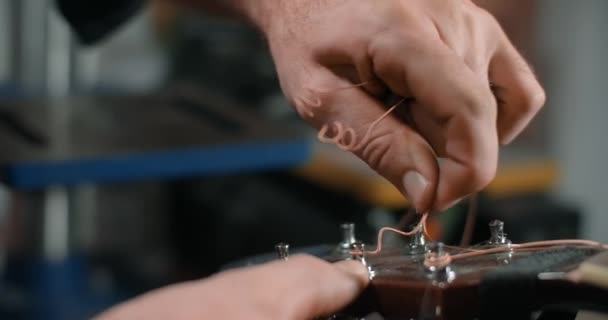 Guitar tech takes off the old strings from the guitar tuners, changing the strings on the acoustic guitar, 4k 60p 10 bit — Stock Video