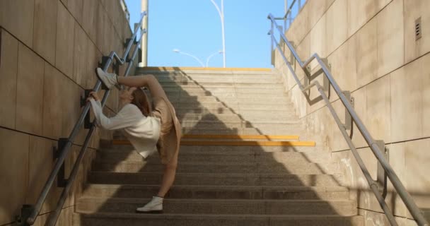 Ung dansare kvinna gör omvända ben gungor på offentliga trappor, 4k 60 fps Prores HQ — Stockvideo