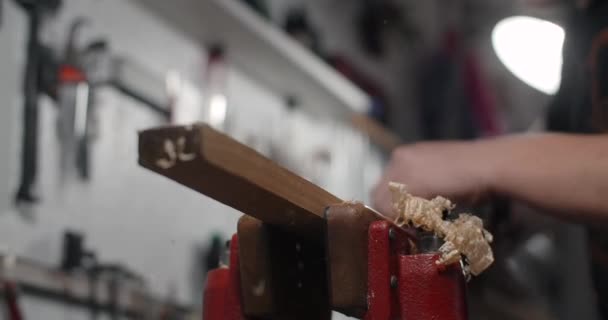 Luthier utiliza el plano de mano para el procesamiento de madera en su taller. Guitarra fabricante utiliza gato plano en cámara lenta, 4k 60p Prores HQ — Vídeo de stock