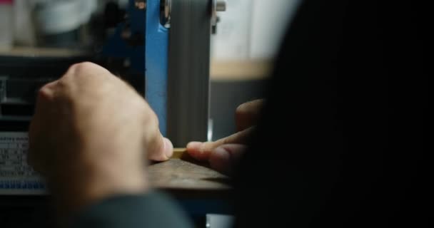 Carpenter utiliza lijadora de cinta en su taller para procesar los pequeños elementos de madera, 4k 60p 10 bit — Vídeo de stock