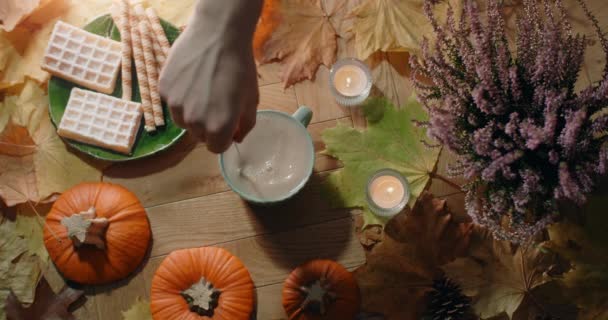 Vídeo de mesa de chá agitando com leite em câmera lenta. Composição de outono decorada em atmosfera quente com waffles, folhas e chá, 4k 60p Prores HQ — Vídeo de Stock