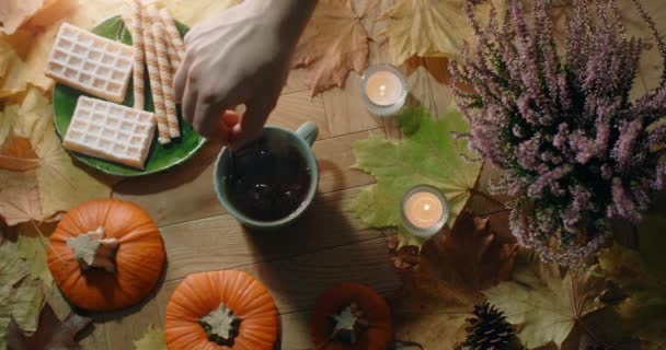 Vidéo de table d'agiter le thé avec du lait au ralenti. Composition d'automne décorée dans une atmosphère chaleureuse avec gaufres, feuilles et thé, siège 4k 60p Prores — Video