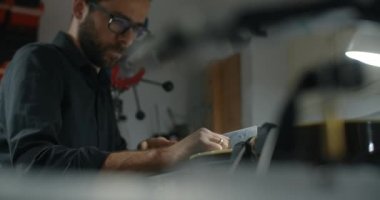 Luthier Sands, müzik aletleri tamir atölyesinde gitar çalıyor. 4k 60fps 10 bit.