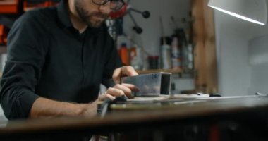 Luthier Sands, müzik aletleri tamir atölyesinde gitar çalıyor. 4k 60fps 10 bit.
