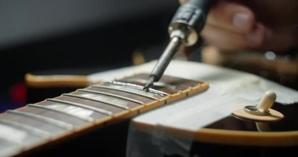Kytara tech zahřívá frets na kytaru pájením železa před refretting, kytara řemeslníci přípravy pro frets nahrazení v elektrické kytary, 4k 60fps Prores HQ — Stock video