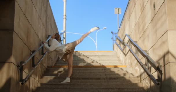 Mulher dançarina jovem está fazendo balanços de perna reversa nas escadas públicas, 4k 60 fps Prores HQ — Vídeo de Stock