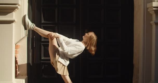 Elastyczna akrobatka wykonuje ćwiczenia rozciągające na starym mieście, rozciągając się publicznie w zwolnionym tempie, 4k 60 fps Prores HQ — Wideo stockowe