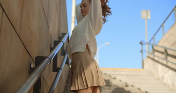 Modèle avec de longues jambes et habillé en mini posent au ralenti dans les escaliers publics, 4k 120 fps Prores HQ — Video