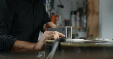 Luthier Sands, müzik aletleri tamir atölyesinde gitar çalıyor. 4k 60fps 10 bit.