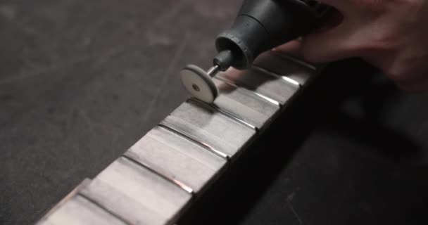 Geigenbauer poliert neue Bünde auf dem Griffbrett der Gitarre in der Instrumentenwerkstatt, 4k 60fps Prores HQ — Stockvideo