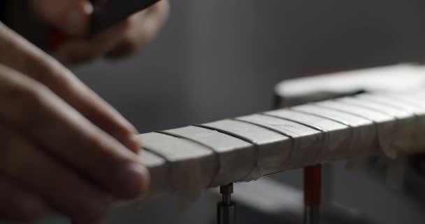 Luthier brousí kytarové držadla v opravně hudebních nástrojů, 4k 60fps 10 bit — Stock video