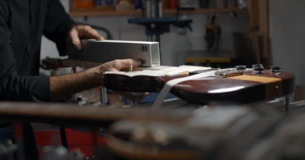 Luthier arenas trastes guitarra en taller de reparación de instrumentos musicales, 4k 60fps 10 bit — Vídeo de stock