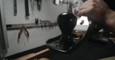 Luthier atölyesinde ahşap işleme için el uçağı kullanıyor. Gitar üreticisi yavaş çekimde kriko uçağı kullanıyor, 4k 60p Prores HQ
