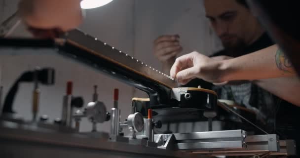 Ηλεκτρική κιθάρα τοποθετείται στο jig στο κατάστημα επισκευής μουσικών οργάνων, 4k 60p 10 bit — Αρχείο Βίντεο