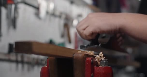 Luthier używa samolotu ręcznego do obróbki drewna w swoim warsztacie. Gitarzysta wykorzystuje płaszczyznę jack w zwolnionym tempie, 4k 60p Prores HQ — Wideo stockowe