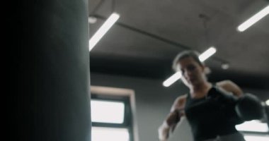 Kadın kickboksör yavaş çekimde boks eldiveni giyer arka planda bulanıklık, boks kulübü eğitimi, 4k 60p Prores HQ