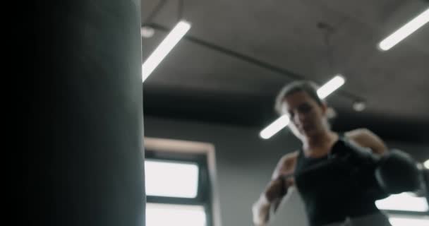Perempuan kickboxer memakai sarung tinju dalam gerakan lambat kabur di latar belakang, pelatihan di klub tinju, 4k 60p Prores HQ — Stok Video