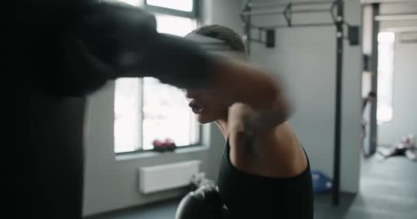 Žena kickboxer v boxerských rukavicích punches boxer bag ve zpomaleném filmu, trénink v boxerském klubu, 4k 60p Prores HQ — Stock video