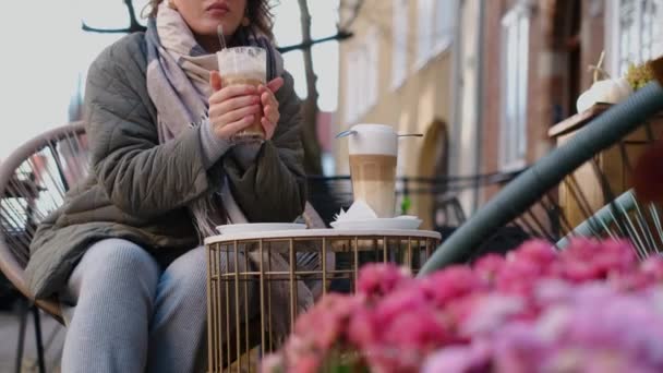 Turistka v slunečních brýlích pije horkou kávu v pouliční kavárně starého města na podzim, 4k 60p zpomalení — Stock video