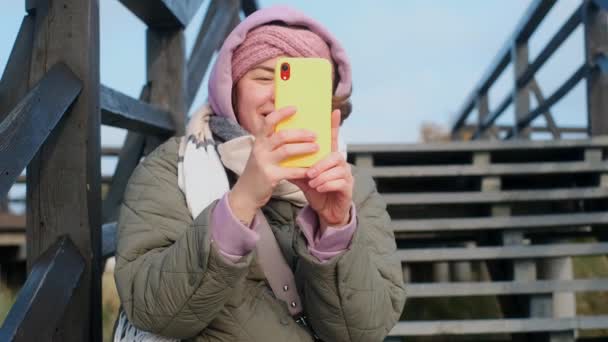 Kalın elbiseli blogcu kadın telefonuyla selfie videosu kaydediyor. Gezgin blogcu kameraya konuşuyor, 4k 60p — Stok video