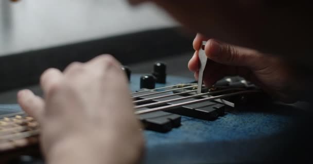 Guitar tech dostosowuje promień struny gitary basowej, naprawa instrumentów muzycznych w warsztacie gitarowym, 4k 60p 10 bit — Wideo stockowe