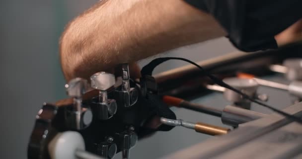 Luthier ajuste la tension sur le cou de la guitare acoustique sur le gabarit. À l'atelier de réparation d'instruments de musique, 4k 60p 10 bits — Video