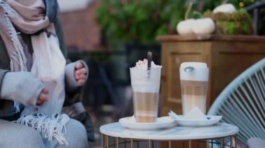 Sonbaharda eski kasabanın sokak kafesinde kaşık kaşık latte karıştırıyor, 4k 60 peni ağır çekim.