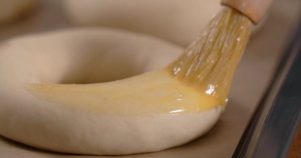 Baker esfrega bagels por gema de ovo com uma escova. Assar a massa, 4k 60p Prores — Vídeo de Stock