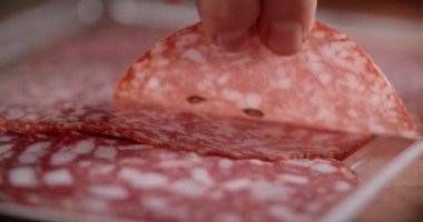 Kadın yavaş çekimde parmaklarından ince bir dilim salam alıyor. Pepperonili yemek, 4k 60p Prores