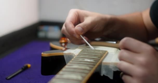 Geigenbauer putzt Bünde auf der Gitarre. Pflege von Musikinstrumenten, 4k 60fps Prores HQ — Stockvideo