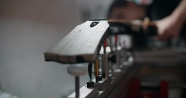 Luthier, müzik aletleri tamir atölyesindeki elektronik gitarı jig 'e monte ediyor, 4k 60p 10 bit.