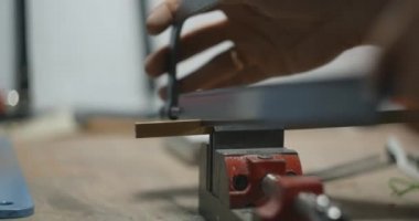 Zanaatkar mengene kıskacına bir parça pirinç testeresi sıkıştırdı. Müzik aletleri için el yapımı parçalar, 4k 60p Prores