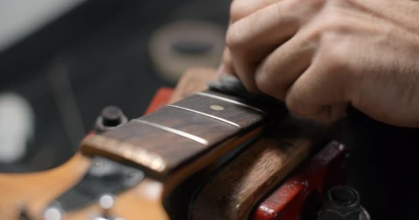 Guitar tech pulisce la tastiera della chitarra al rallentatore, negozio di servizi di chitarra, 4k 60p 10 bit — Video Stock