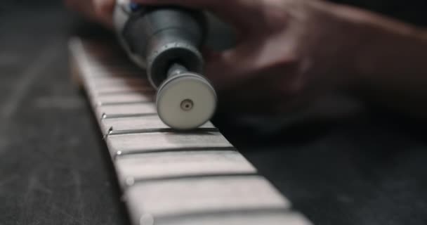 Luthier, müzik aletleri tamirhanesinde, 4k 60fps Prores karargahında gitar fretboardunda yeni perdeler parlatıyor. — Stok video