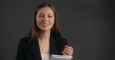 Siyah takım elbiseli genç kadın, koloniciyi gülümseyerek dinler ve not defterine notlar alır, anket yapar, röportaj yapar, 4k Prores karargahı