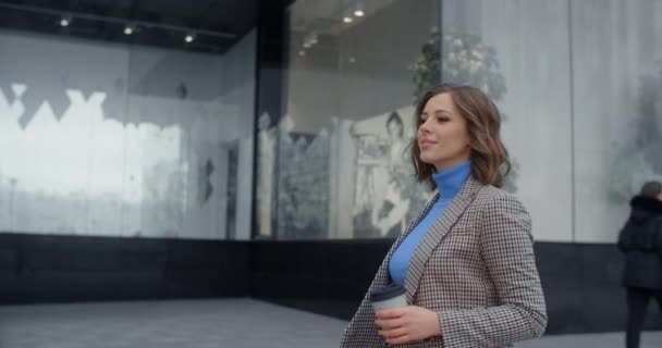 Portrait de la jeune femme confiante, qui sourit et se promène dans la ville avec un café à la main, marchant au travail au centre-ville, 4k Prores HQ 10 bit — Video