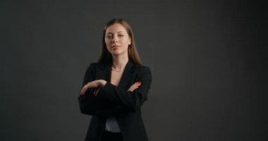 Siyah takım elbiseli hırslı iş kadını kameraya bakıyor, elleri bağlı, kapalı poz, 4k Prores karargahı.