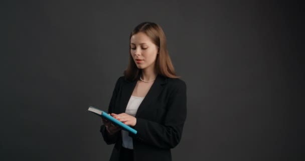 Femme d'affaires en costume parcourt les pages du journal, jeune femme cherche des notes dans le bloc-notes papier, siège 4k Prores — Video