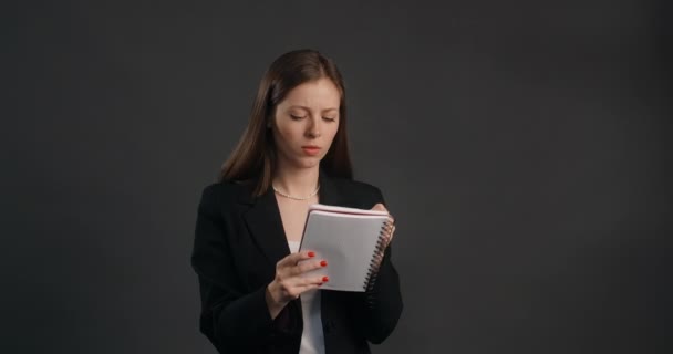 Mujer exasperada y enojada en traje negro cruza sus notas en el bloc de notas, arruga la hoja de papel y la tira, 4k Prores HQ — Vídeo de stock