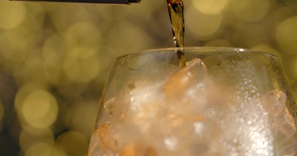 MACRO SHOT of the pouring alcohol to the cocktail glass full of ice cubes, brandy is poured to the glass, 4k 120fps Prores HQ — Stockvideo