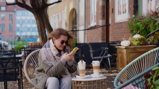 Traveller woman in sunglasses does does photos of her coffe cups by smartphone in the street cafe of old town, 4k 60p slow motion — Stock video