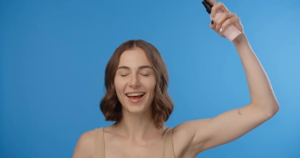 Woman sprays hair mask to her head. Womens cosmetics usage. Beauty care procedures on blue screen, 4k Prores HQ — Stock Video