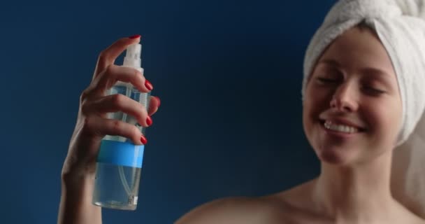 Woman in the towel sprays tonic water after bath. Womens cosmetics usage. Beauty care procedures on blue screen, 4k Prores HQ — 图库视频影像
