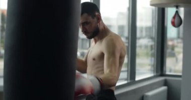 Kickboxer punches boxer bag by his arms and legs in slow motion at training, training at the fightclub, mixed martial arts, 4k 60p Prores