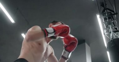 Boxer man in red boxing gloves punches boxer bag in slow motion, training in boxing club, 4k 60p Prores HQ
