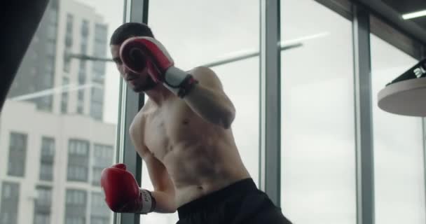 Кікбоксер ударяє боксерську сумку руками і ногами у повільному русі на тренуваннях, тренуваннях у бойовому клубі, змішаних бойових мистецтвах, 4k 60p — стокове відео