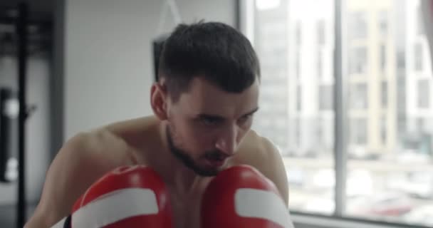 Boxer man in red boxing gloves punches boxer bag in slow motion, training in boxing club, 4k 60p Prores HQ — Stock video